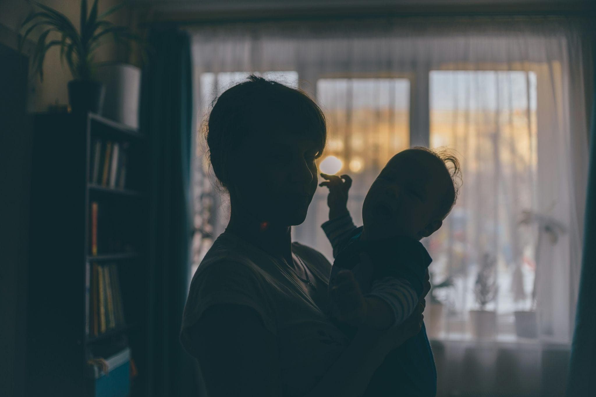 A parent holding a baby in silhouette