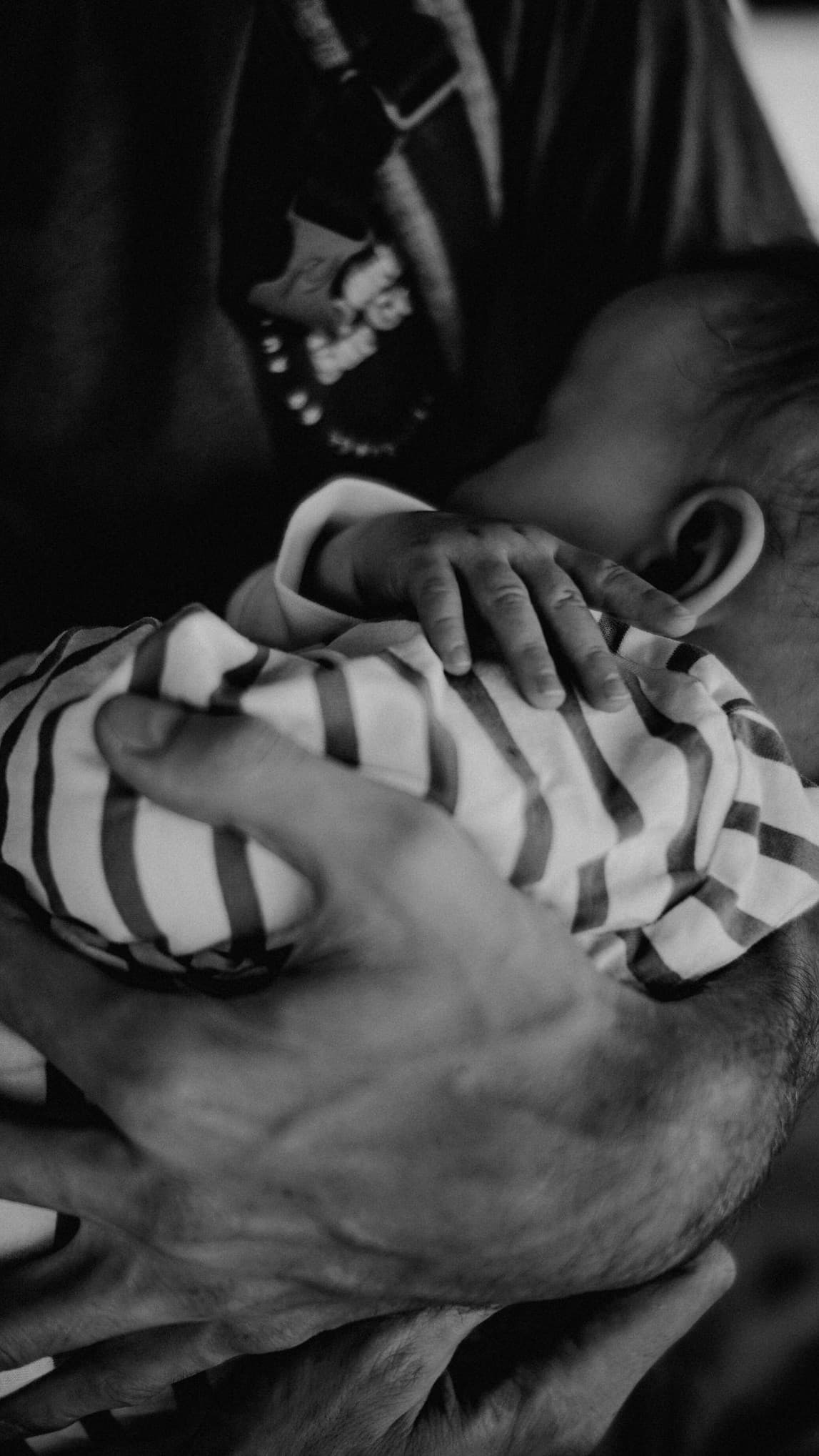 An adult holding a newborn's hand